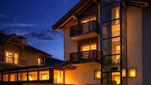 A modern building with a balcony and a glass structure. - Villa Rosa (Campitello di Fassa)