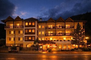 Un hotel de varios pisos con balcones, una entrada central y un letrero que dice 'Hotel Villa Rosa'.