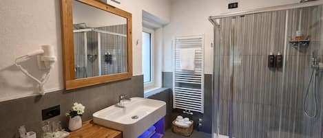 Un baño moderno con tocador de madera, un espejo grande, cabina de ducha de vidrio y un perchero para toallas.