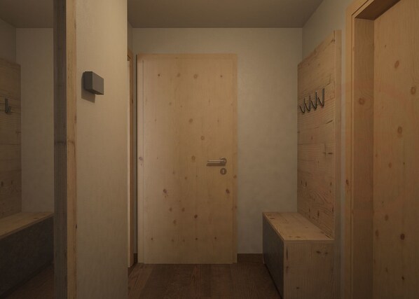 A wooden door with a handle, a small bench, and a wall-mounted light fixture. - Alpino Al Cavalletto (Canazei)