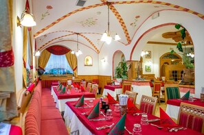 Un restaurante con techos altos en arco, manteles rojos y decoración tradicional.