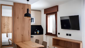 Ein modernes Hotelzimmer mit einem Holztisch, zwei Stühlen, einem an der Wand befestigten Fernseher und einem großen Spiegel.