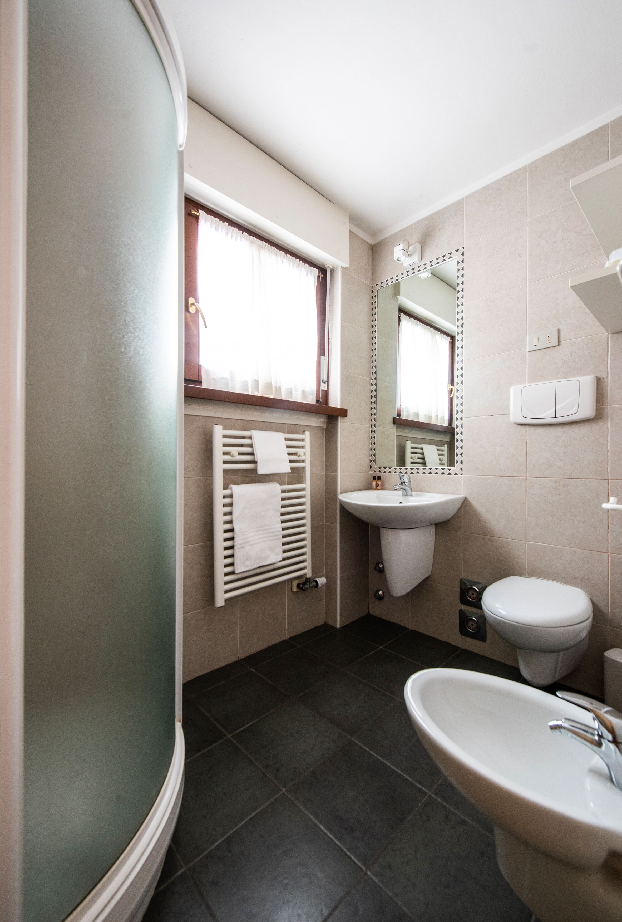 A bathroom with a white sink, a toilet, a mirror, and a towel rack.