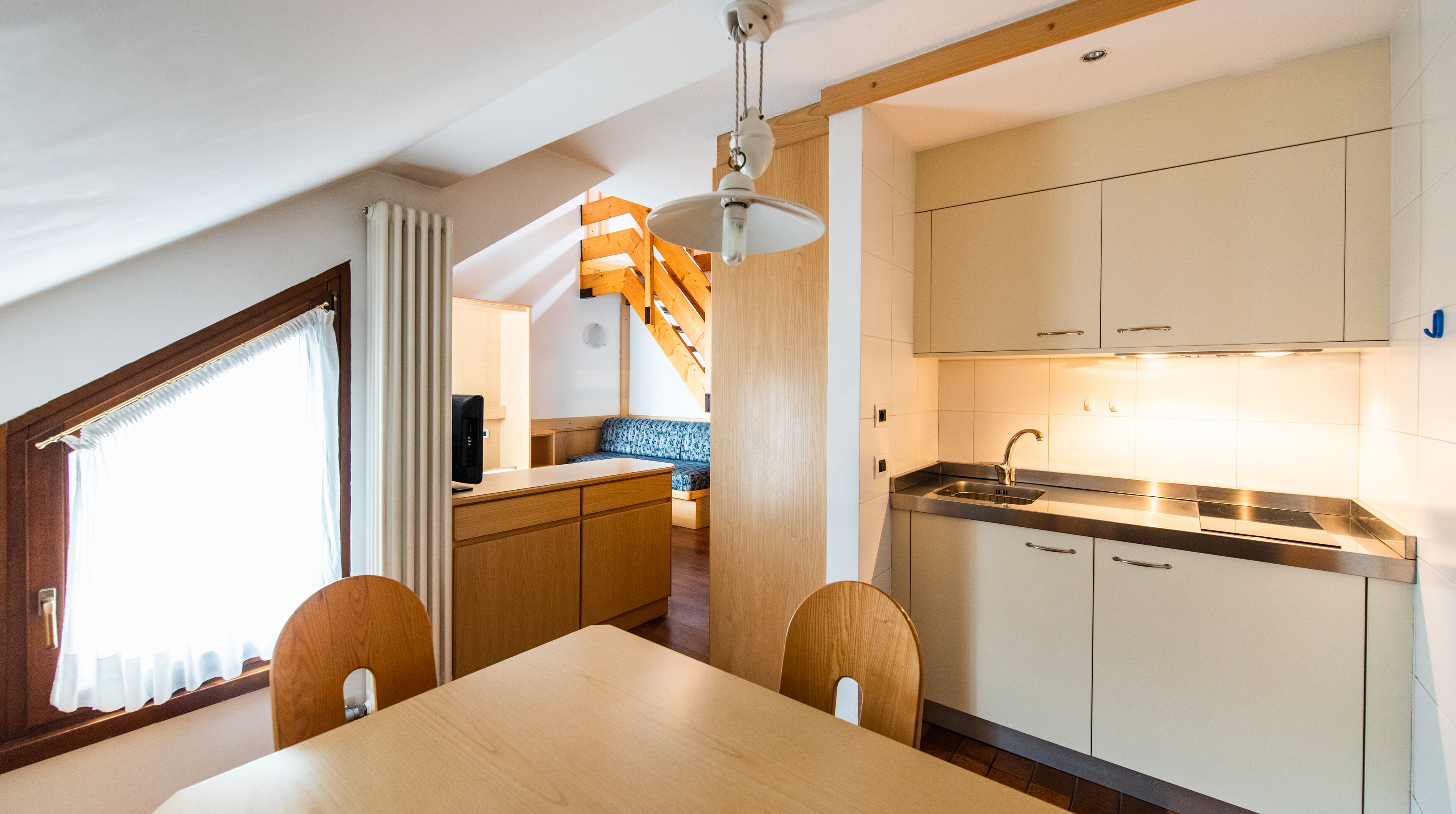 A compact kitchen with wooden cabinets, a sink, and a dining area with a table and chairs.