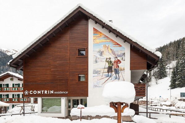 A wooden mountain lodge with a large mural of skiers on the side.