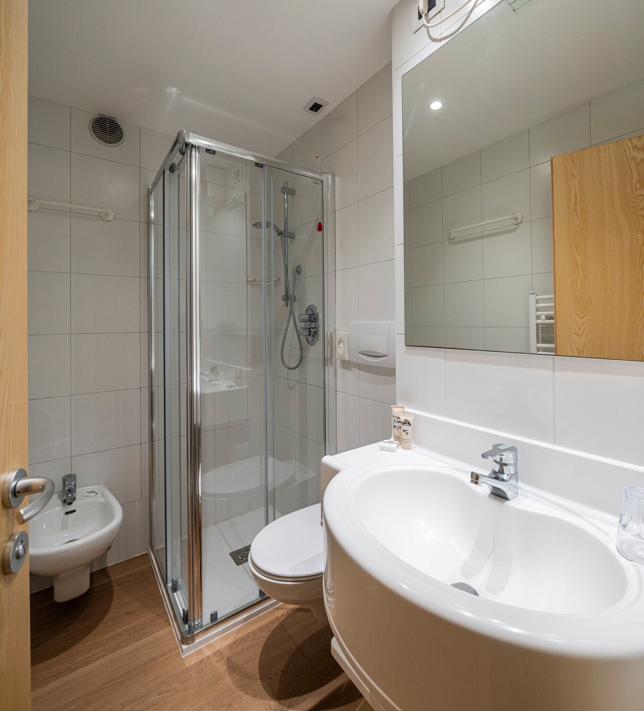 A modern bathroom with a glass-enclosed shower, a white sink, and a toilet.