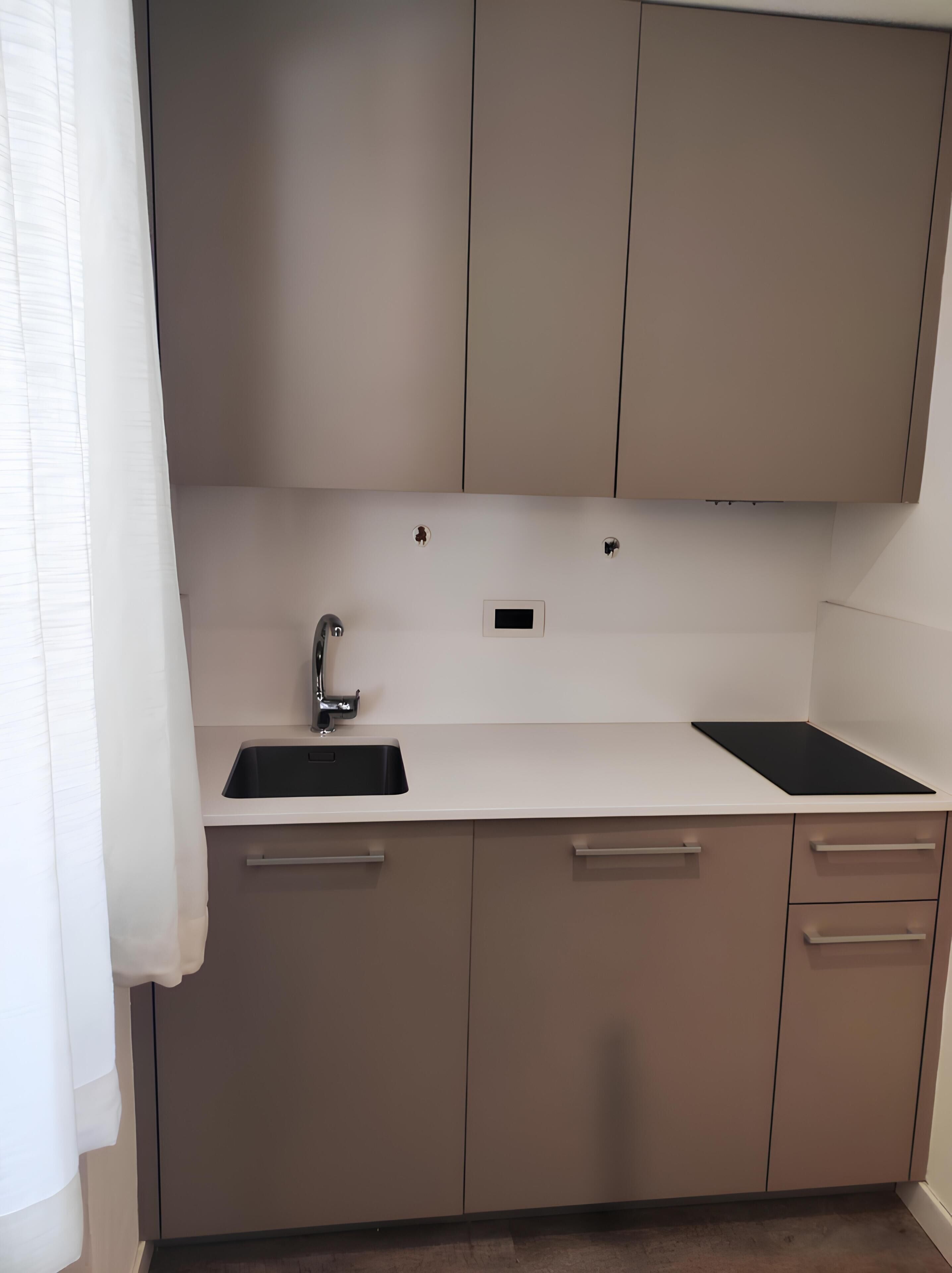A modern kitchen with a white countertop, a sink, and beige cabinets.