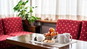 Ein Frühstückstisch mit roter Sitzgelege, einem Topfpflanzen und einem fenster mit Vorhängen.