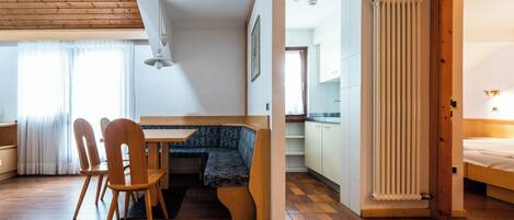 Una habitación acogedora con techo de madera, una mesa de comedor con sillas, un banco, un radiador y una cama.