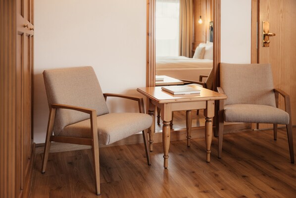 A room with two wooden chairs, a small wooden table, and a mirror on the wall. - Diana Dolomites  (Badia)