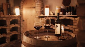 A wooden barrel with two wine glasses and a bottle of wine, set against a brick wall with a lit candle. - Diana Dolomites  (Badia)