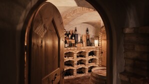 An arched doorway leading to a wine cellar with wooden racks and barrels. - Diana Dolomites  (Badia)