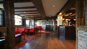 A restaurant with wooden beams, red chairs, a bar area, and a red carpet. - Premier Inn Manchester - Handforth (Wilmslow)