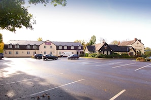 A parking lot with cars, a building labeled 'Premier Inn,' and another building with a sign 'The Bulls Head.' - Premier Inn Manchester - Handforth (Wilmslow)