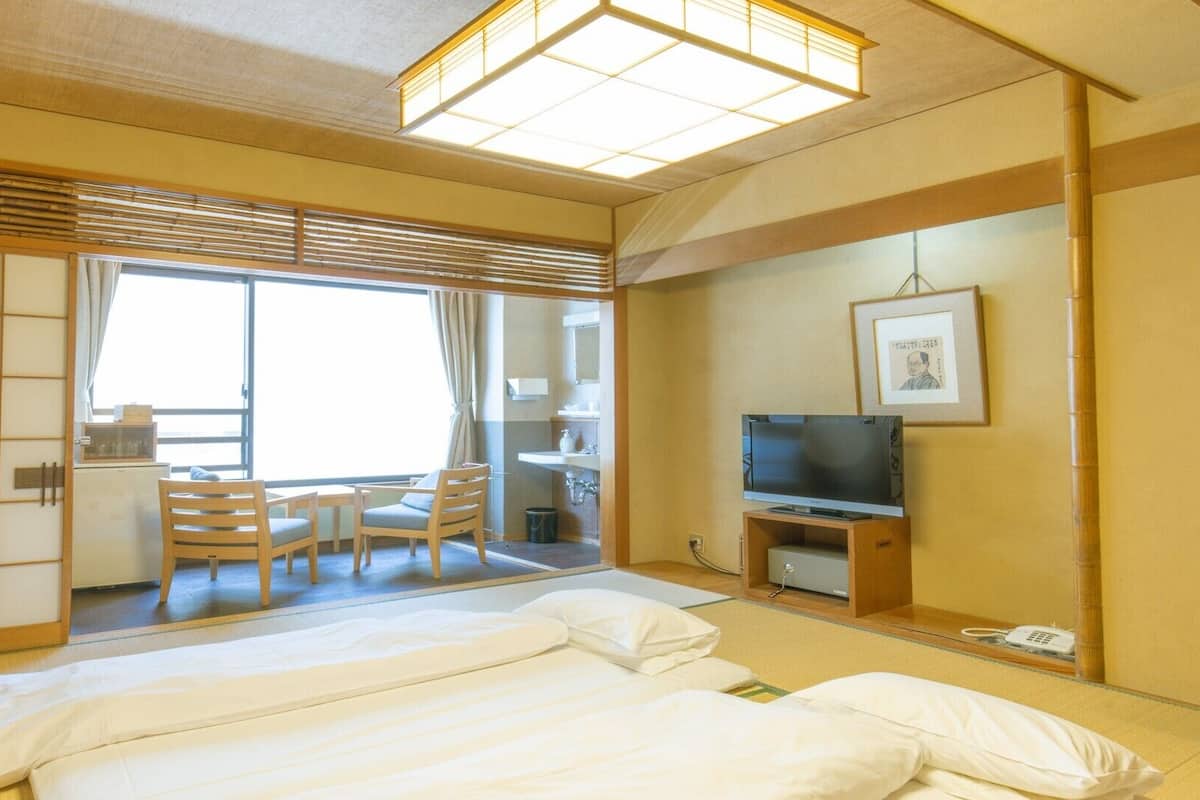 Une chambre d’hôtel comprenant un lit, une télévision, un bureau avec une chaise et une fenêtre.
