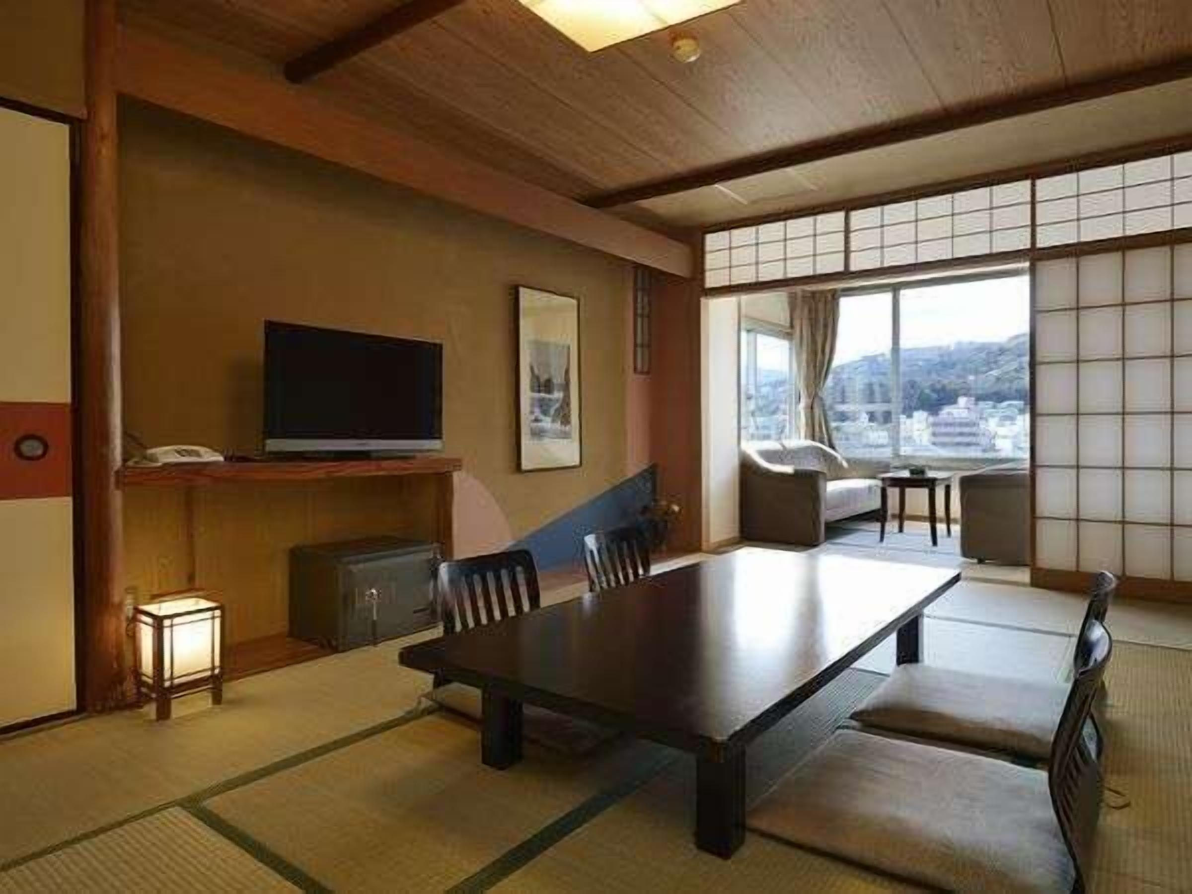 A traditional Japanese-style room with tatami flooring, a low table, and a television.