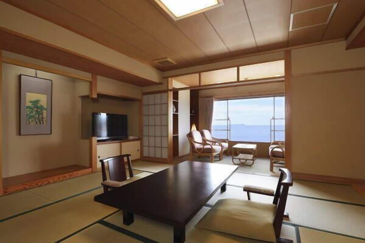 Une pièce de style japonais traditionnel, avec un sol recouvert de tatamis, une table basse et un téléviseur.
