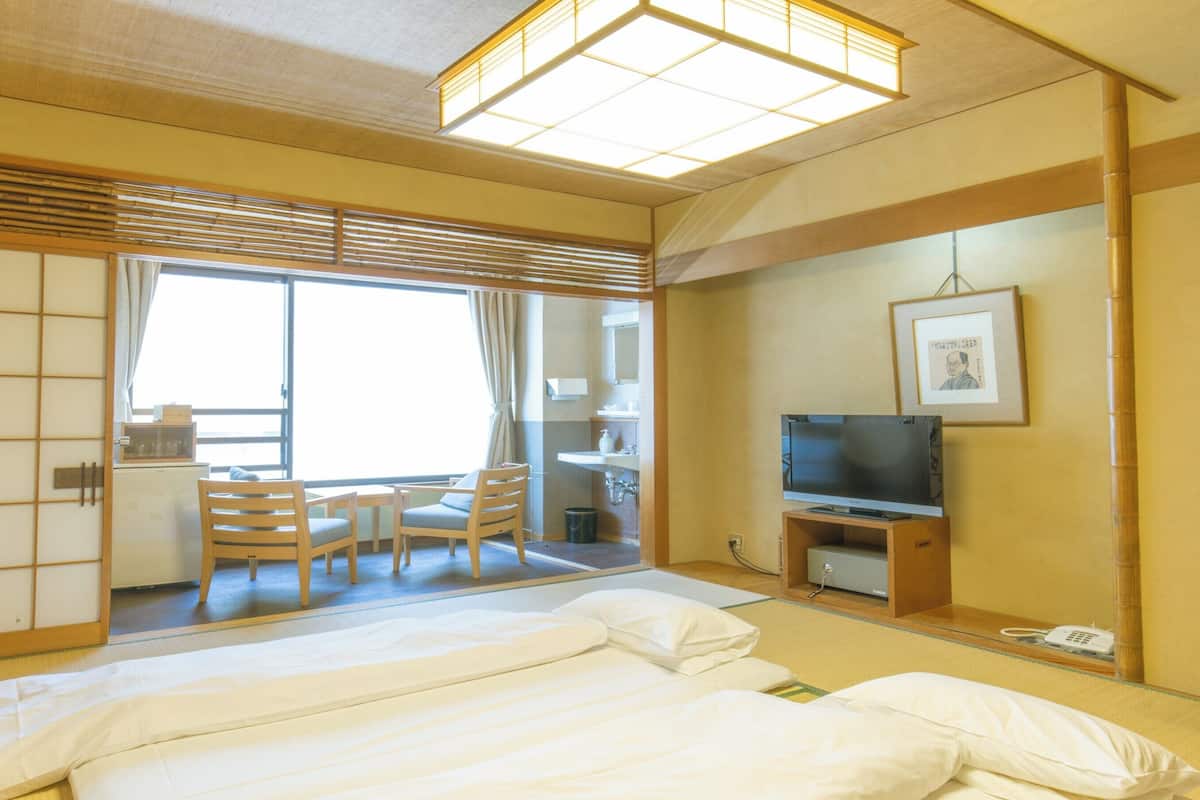 Une chambre d’hôtel avec un lit, un bureau, une chaise, une télévision et un tableau au mur.