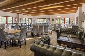 A dining area with wooden beams, patterned chairs, a leather sofa, and a table with a vase. - Roydon Marina Village (Harlow)