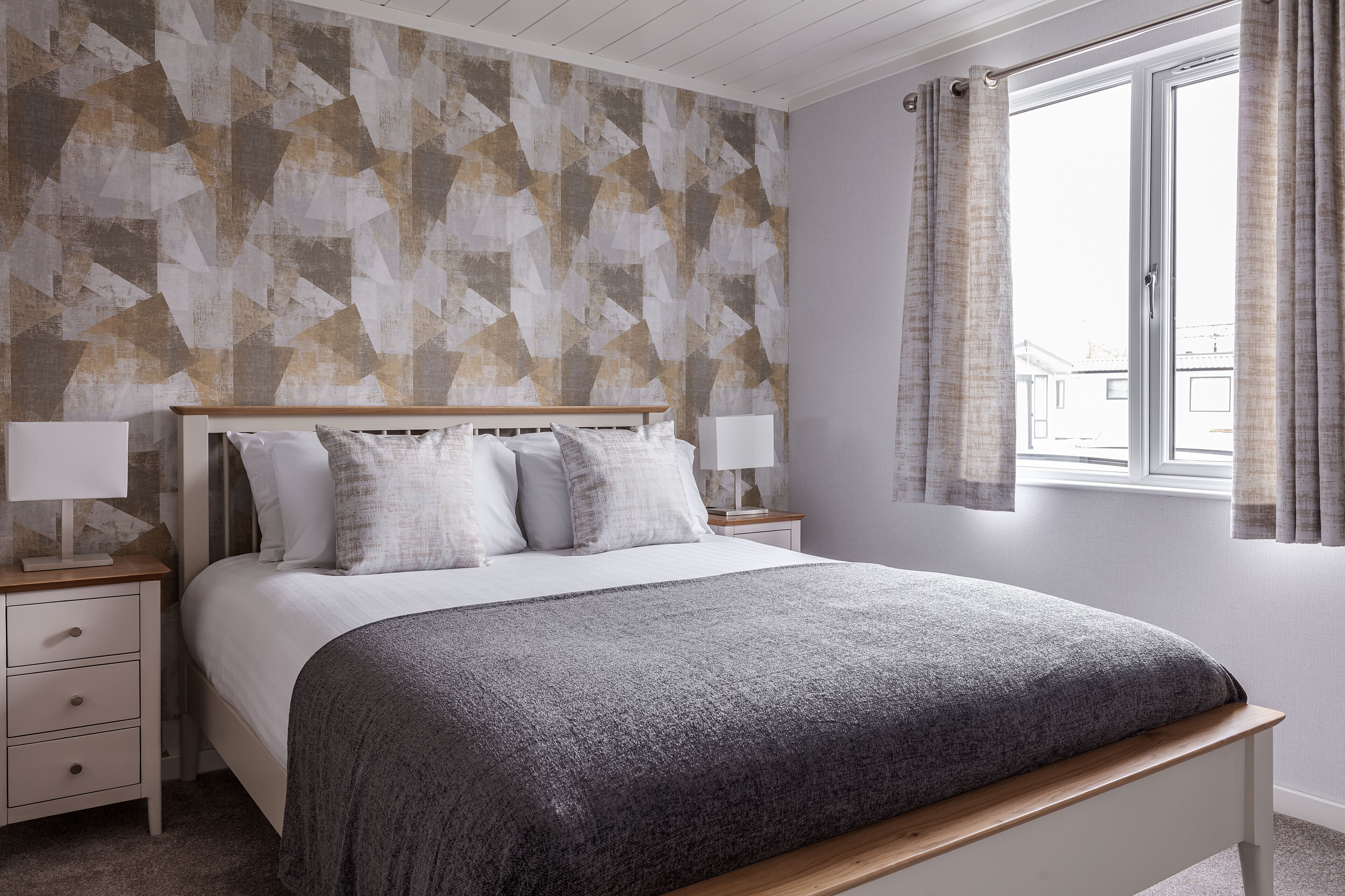 A bedroom with a bed, bedside tables, and a window with curtains.
