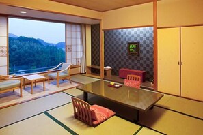 Una habitación japonesa tradicional con suelo de tatami, una mesa baja y vistas al exterior.