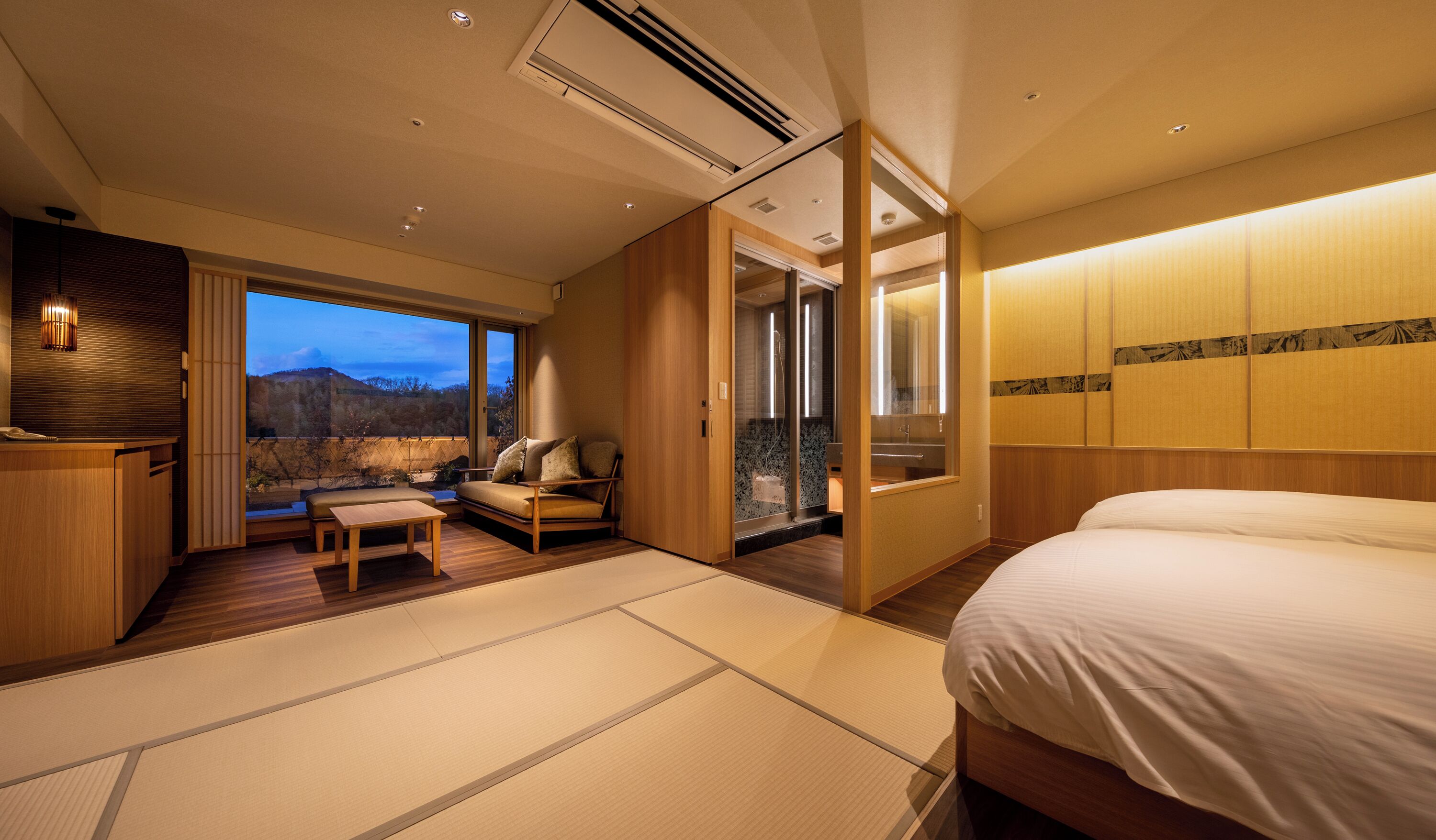 Ein Hotelzimmer mit Bett, einer Sitzecke mit Aussicht, einer Schiebetür zu einem Balkon und einem Holzbüro.