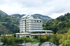 A multi-story hotel with a flat roof, surrounded by lush greenery and mountains. - Izu Nagaoka Hotel Tenbo (Izunokuni)