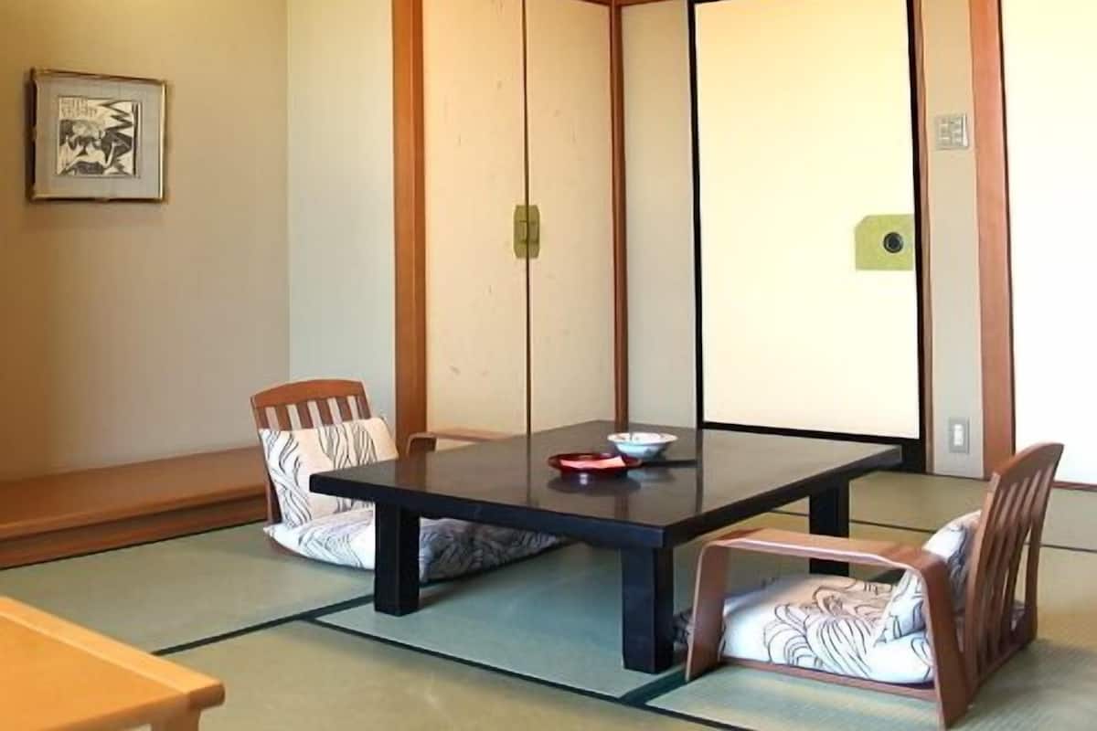Une pièce de style japonais traditionnel, avec un sol recouvert de tatamis, une table basse et des meubles en bois.