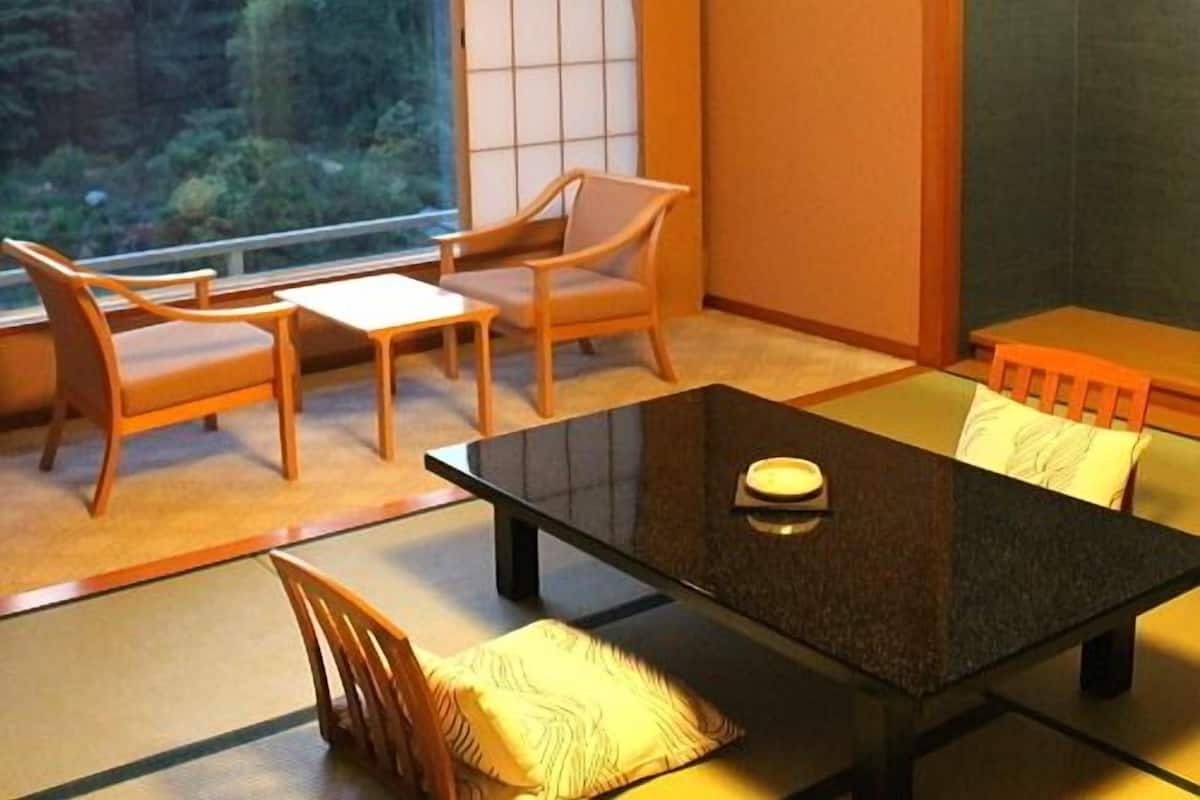 Une pièce avec une grande fenêtre, une table noire, des chaises en bois et un canapé.