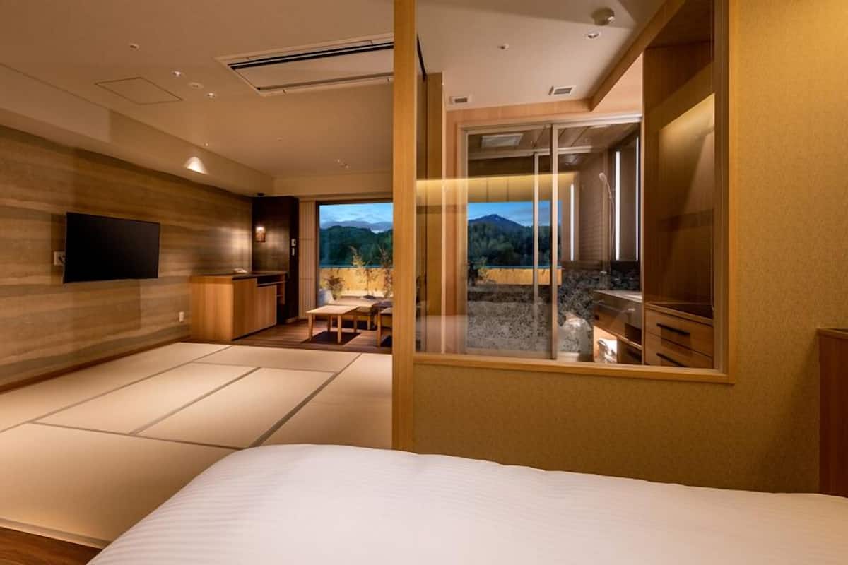 Une chambre d’hôtel moderne dotée d’un grand lit, d’une télévision, d’un coin repas et offrant une vue sur les montagnes.