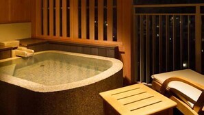 A hot tub with a wooden deck and a chair, set against a night sky. - Izu Nagaoka Hotel Tenbo (Izunokuni)