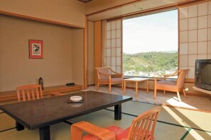 Una habitación tradicional japonesa con suelo de tatami, una mesa baja y puertas correderas.