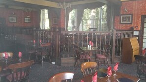 Un restaurante con mobiliario de madera, una zona de bar y amplios ventanales.
