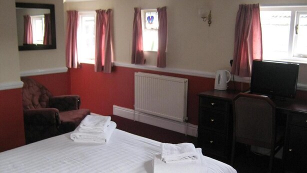 Habitación de hotel con cama, escritorio, silla, radiador y televisor.