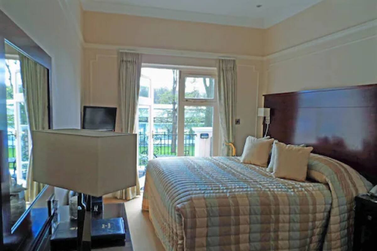 A hotel room with a large bed, a TV, and a view of the outdoors.