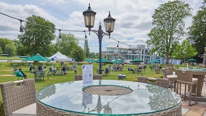 An outdoor seating area with wicker chairs and a glass-top table, surrounded by string lights and a gazebo in the background. - Phyllis Court Members Club (Henley-on-Thames)