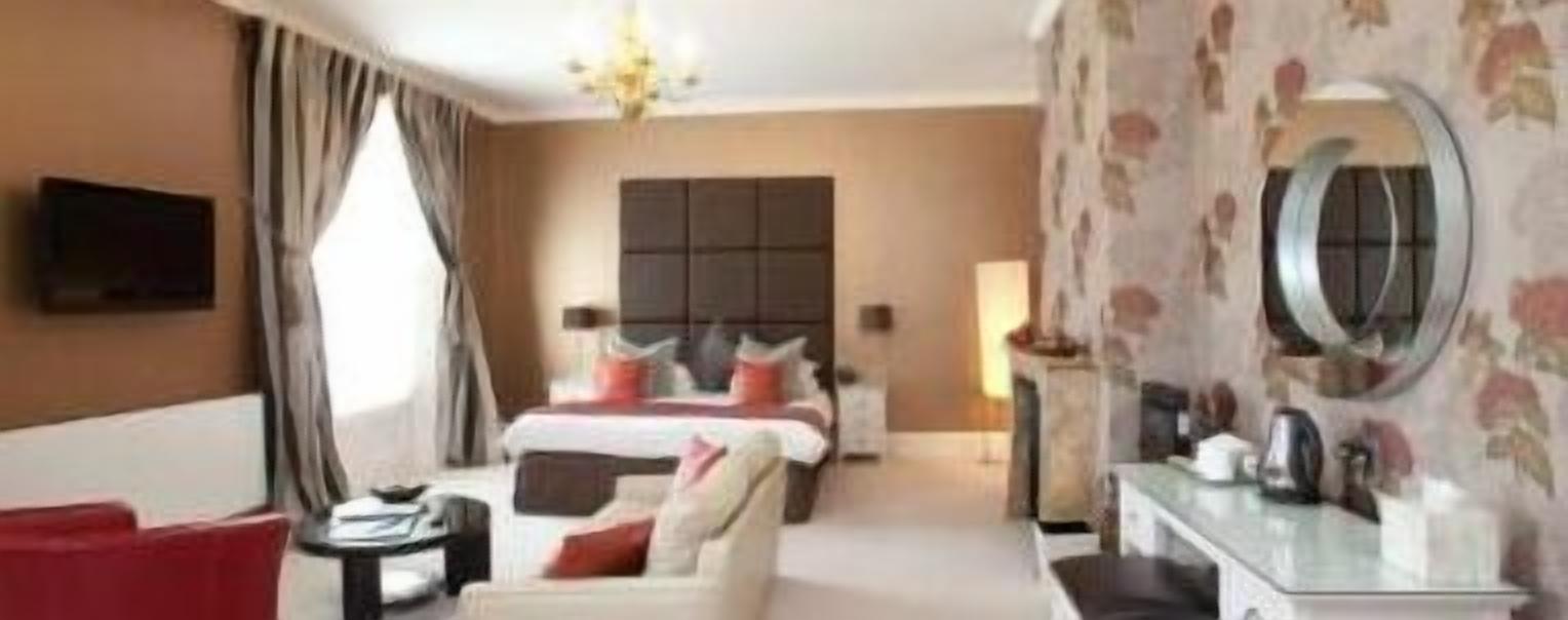 Habitación de hotel con cama, sofá, escritorio y televisor.