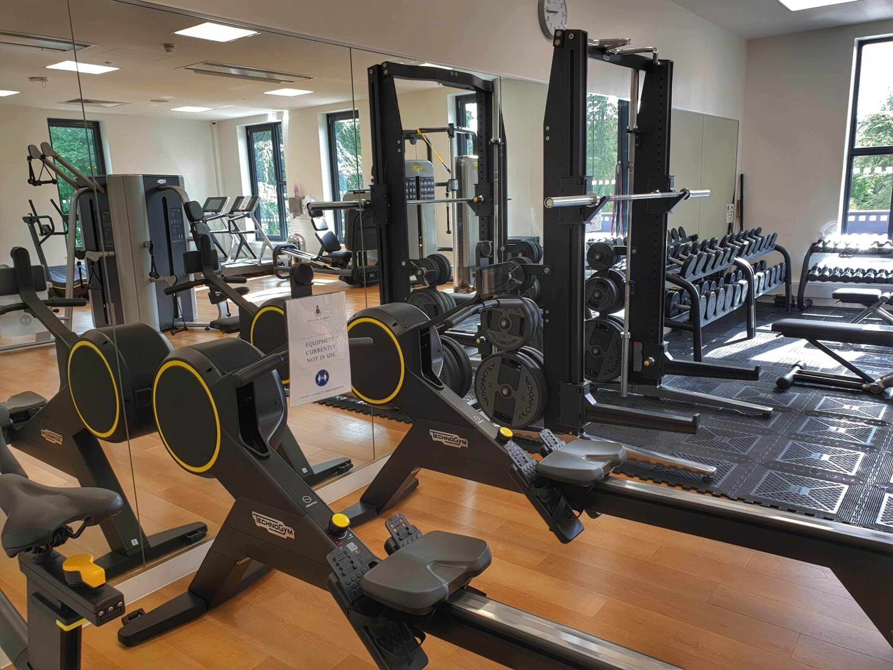 A gym with cardio machines, weightlifting equipment, and dumbbells.