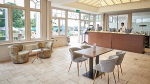 A spacious indoor area with large windows, a bar area, and seating arrangements. - Phyllis Court Members Club (Henley-on-Thames)