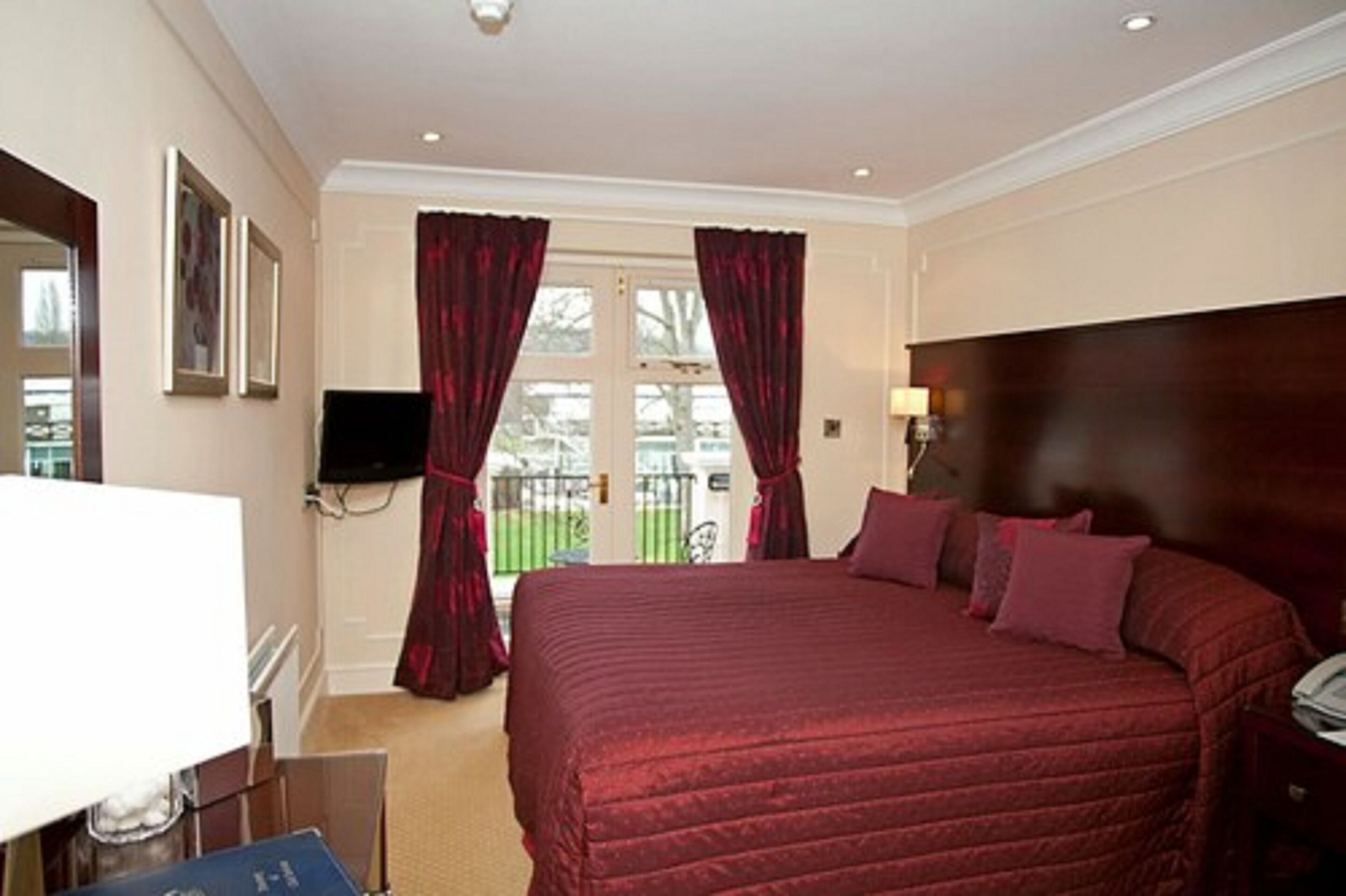 Habitación de hotel con una cama grande, televisión y vistas a un jardín por la ventana.