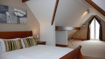 Un dormitorio con una cama de madera, un cuadro en la pared y un techo inclinado.