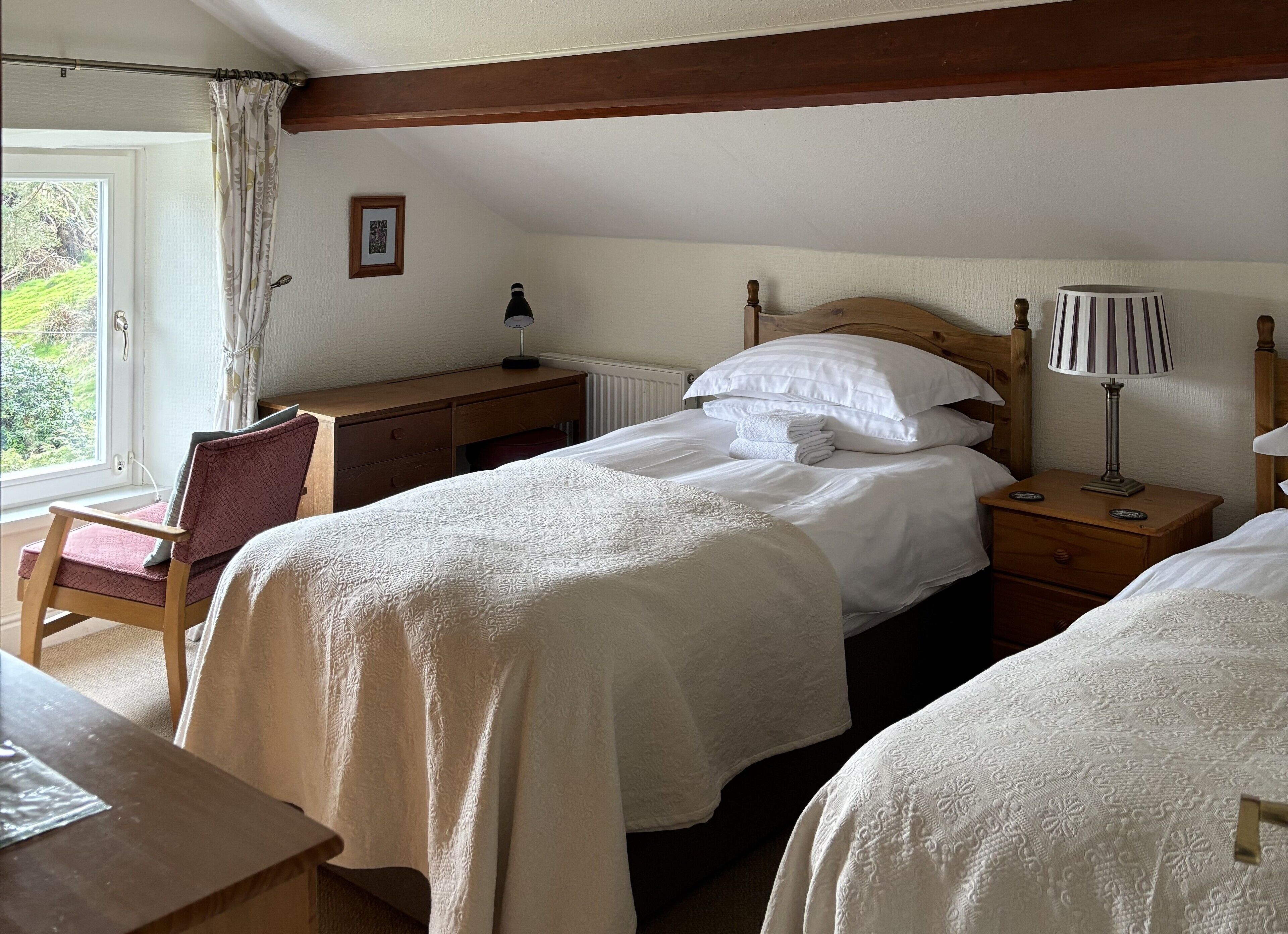 A bedroom with a bed, bedside tables, a desk, a chair, and a window with curtains.