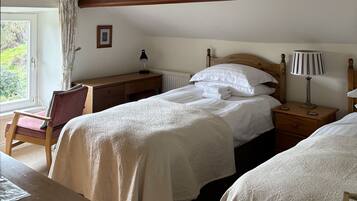 A bedroom with a bed, bedside tables, a desk, a chair, and a window with curtains.