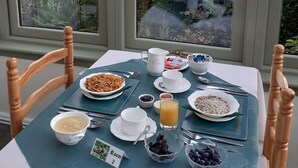 Una mesa de desayuno con diversos platos, vista a un paisaje boscoso a trav és de amplias ventanas y un cartel con el número de habitación.