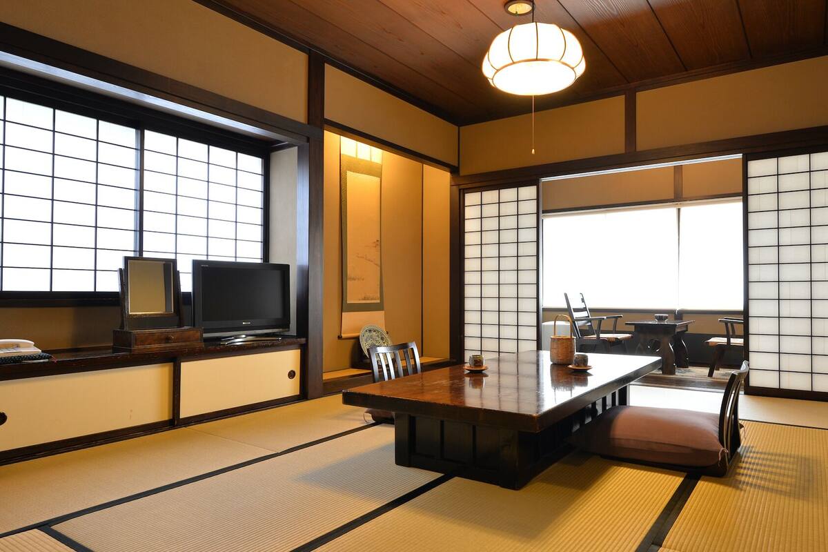 Une pièce de style japonais traditionnel, avec un sol recouvert de tatamis, une table basse et des portes coulissantes.