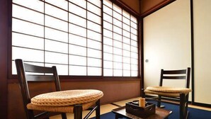 A traditional Japanese room with tatami flooring, two wooden chairs, a small table, and a sliding door. - Ryokan Sugimoto (Matsumoto)