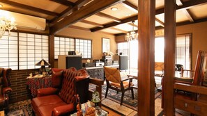 Uma sala de estar tradicional japonesa com tatames, uma mesa de madeira baixa e um sofá.