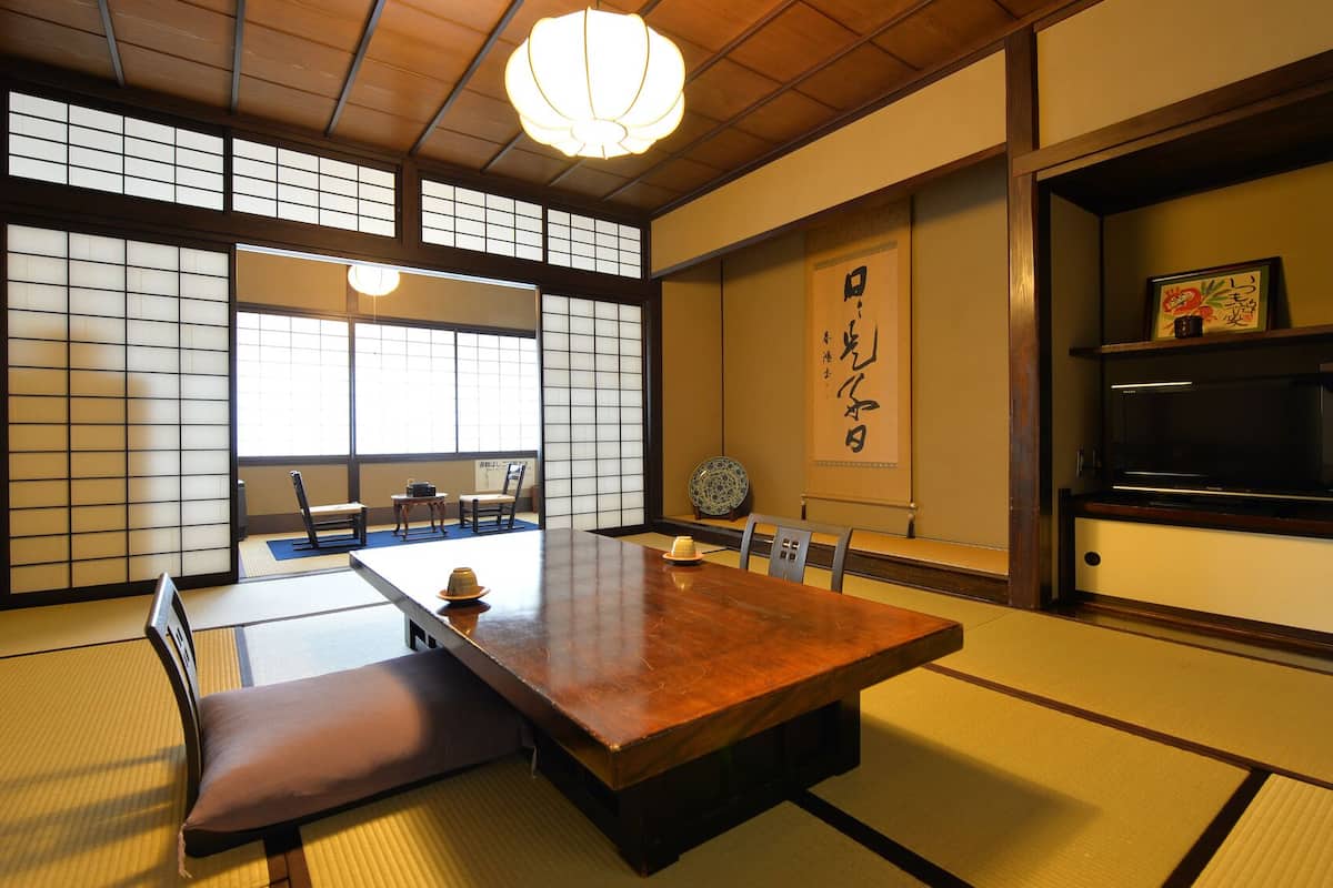Une pièce de style japonais traditionnel, avec un sol recouvert de tatamis, une table basse et des portes coulissantes.