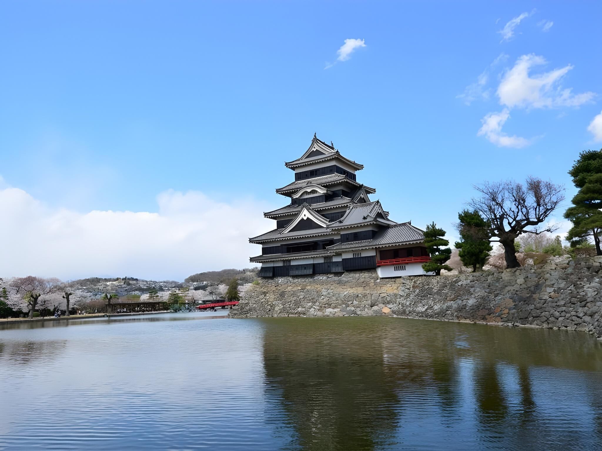 A traditional Japanese pagoda with a reflection in the water, surrounded by stone walls and trees.