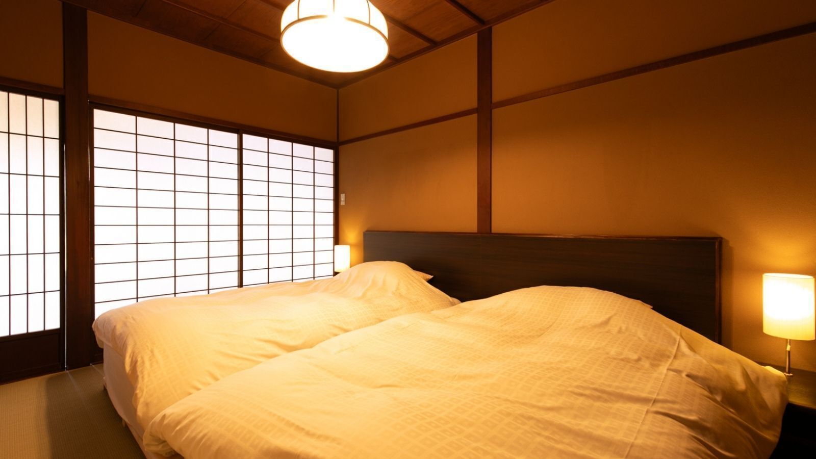 Een traditionele Japanse slaapkamer met tatami vloerbedekking, een laag houten hoofdeinde en een shoji schuiframen.